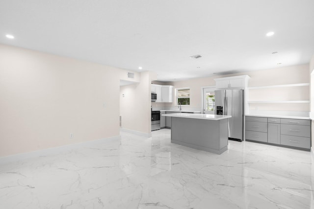 kitchen with white cabinets, stainless steel appliances, sink, gray cabinetry, and a center island