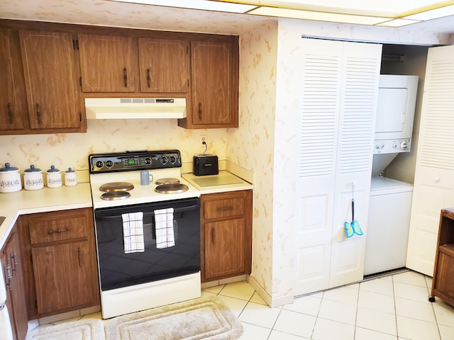 kitchen featuring stacked washing maching and dryer, electric range, and light tile patterned floors