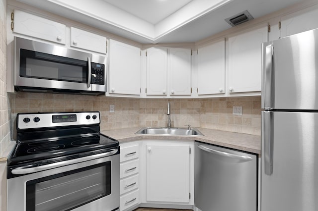 kitchen with backsplash, sink, white cabinets, and stainless steel appliances