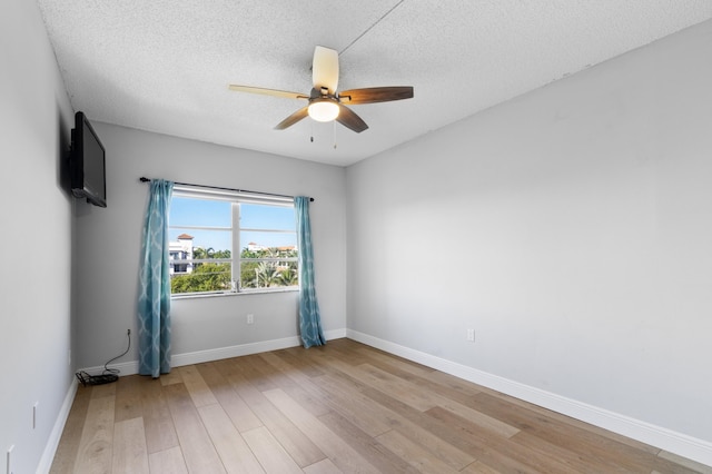 empty room featuring ceiling fan, light hardwood / wood-style flooring, and a textured ceiling