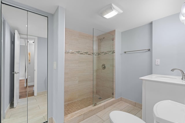 bathroom featuring tile patterned flooring, a tile shower, vanity, and toilet