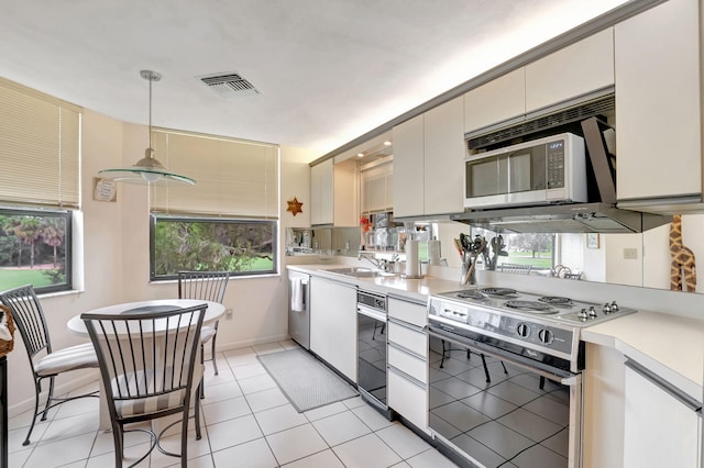 kitchen with light tile patterned floors, range, sink, and pendant lighting