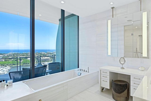 bathroom featuring tile patterned flooring, tile walls, a water view, vanity, and tiled bath