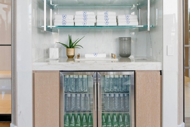 bar featuring wine cooler, light brown cabinetry, and light stone counters