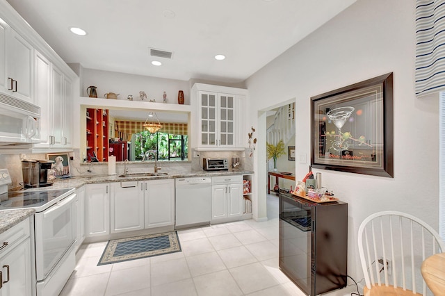 kitchen with white appliances, tasteful backsplash, sink, white cabinets, and light stone counters