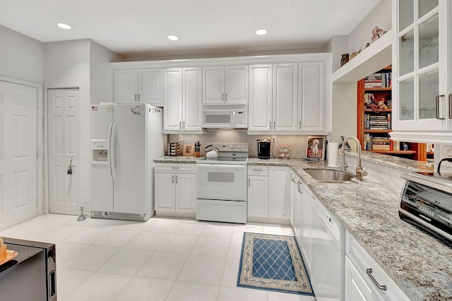 kitchen with sink, white cabinetry, light stone counters, and white appliances