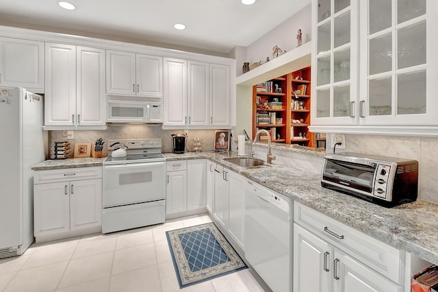 kitchen with light tile patterned flooring, white cabinetry, sink, and white appliances