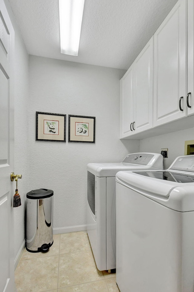 washroom featuring cabinets, independent washer and dryer, a textured ceiling, and light tile patterned flooring