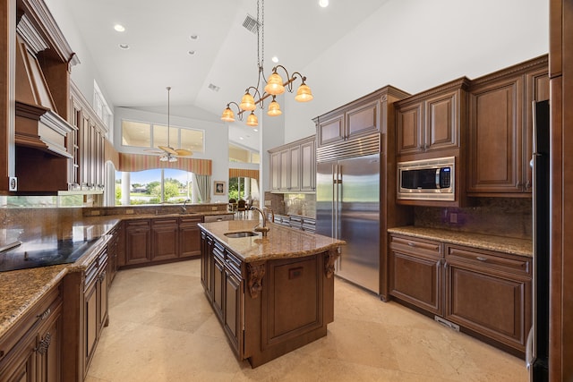 kitchen featuring an island with sink, backsplash, decorative light fixtures, built in appliances, and high vaulted ceiling