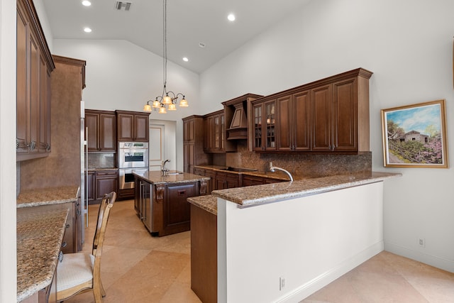 kitchen with kitchen peninsula, tasteful backsplash, high vaulted ceiling, decorative light fixtures, and a center island