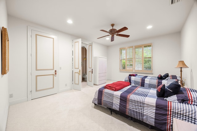 bedroom featuring ceiling fan, ensuite bath, and light colored carpet