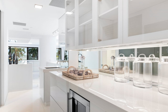 interior space featuring wine cooler, sink, white cabinets, and light tile patterned flooring