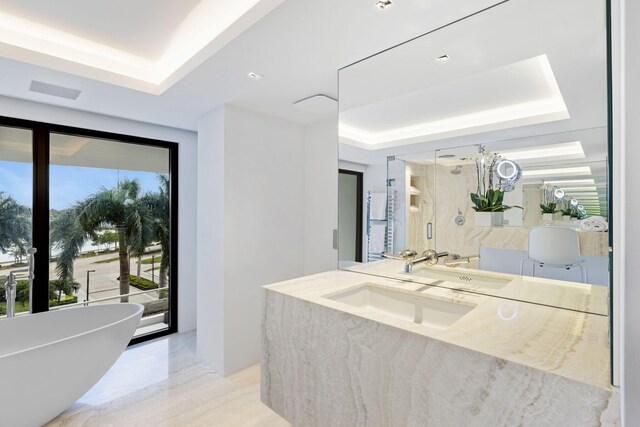 bathroom with vanity, shower with separate bathtub, and a tray ceiling