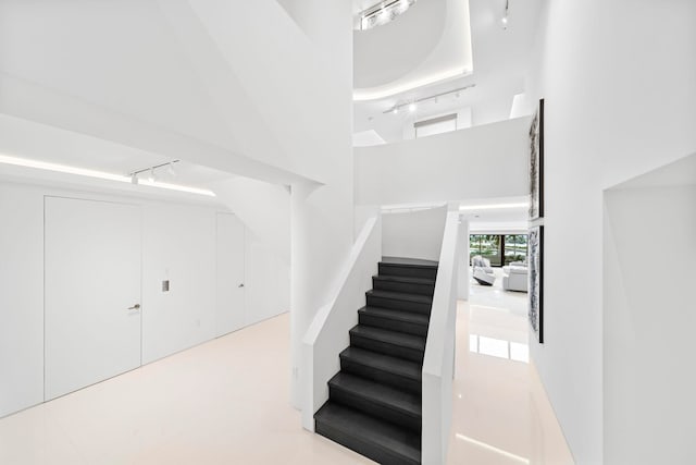 stairs featuring a towering ceiling and rail lighting