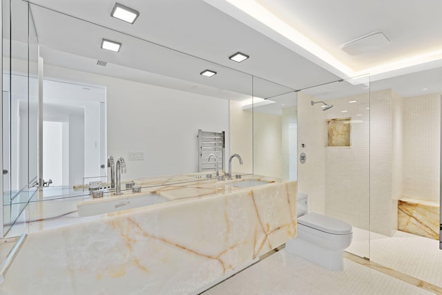 bathroom with a tile shower, toilet, and vanity