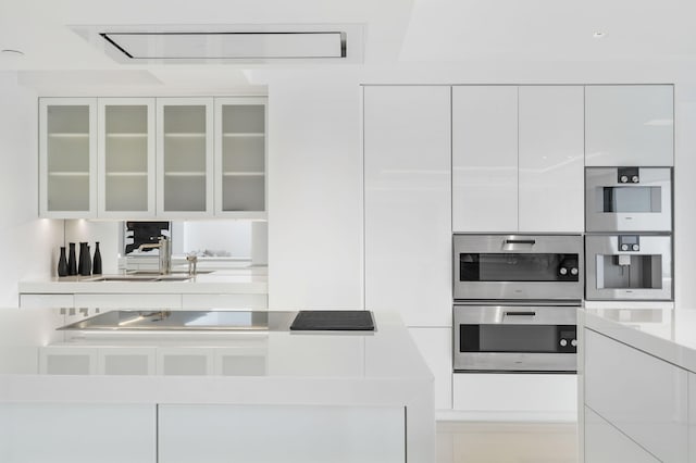 kitchen featuring white cabinetry, double oven, and sink