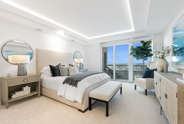 bedroom with light carpet, a tray ceiling, and access to outside