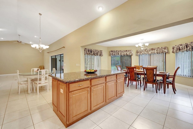 kitchen featuring light tile patterned floors, dark stone countertops, a kitchen island, decorative light fixtures, and vaulted ceiling