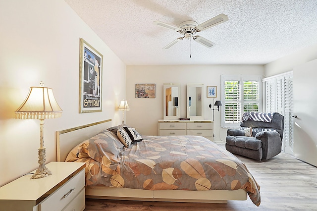 bedroom with a textured ceiling, light hardwood / wood-style flooring, and ceiling fan