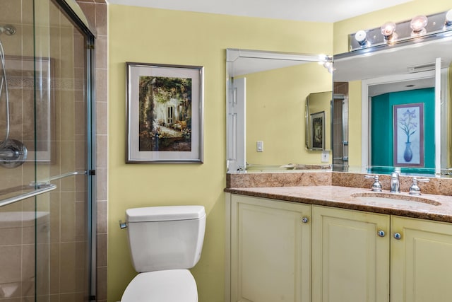 bathroom featuring toilet, vanity, and a shower with door