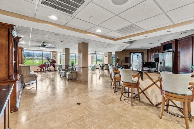 kitchen with a paneled ceiling, a kitchen bar, plenty of natural light, and stainless steel fridge with ice dispenser