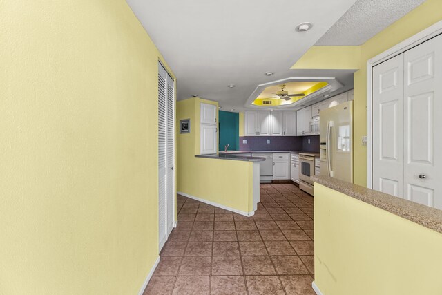 9500 S Ocean Dr Unit 1909, Jensen Beach, FL 34957 - kitchen featuring white appliances, ceiling fan, a raised ceiling, white cabinetry, and baseboards