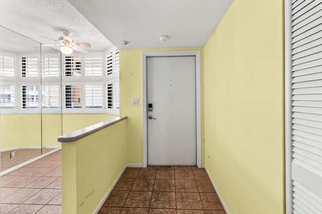 interior space featuring a textured ceiling, a healthy amount of sunlight, tile patterned flooring, and ceiling fan