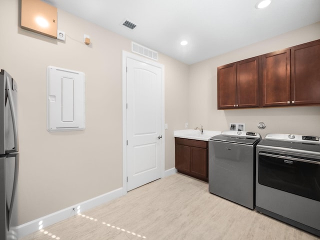 laundry room featuring cabinets, light wood-type flooring, washer and clothes dryer, and sink