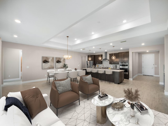 living room with a chandelier, light wood-type flooring, sink, and a tray ceiling