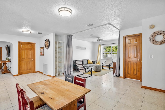 dining room with a textured ceiling, light tile patterned floors, and ceiling fan