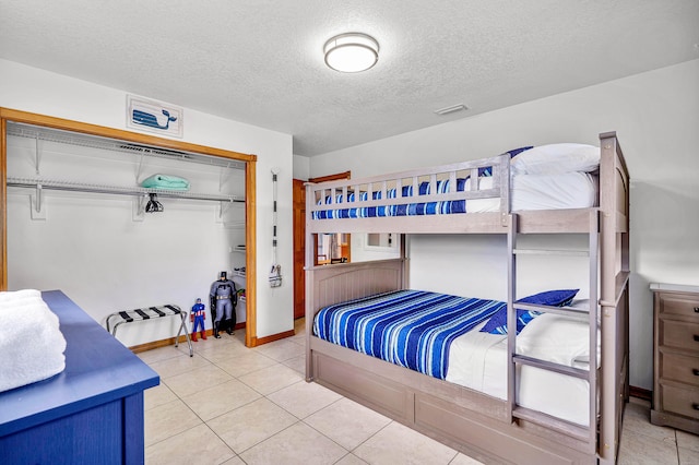 bedroom featuring a closet, a textured ceiling, and light tile patterned floors