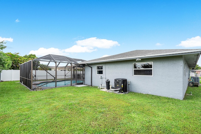 back of property with a lawn, a fenced in pool, and a lanai