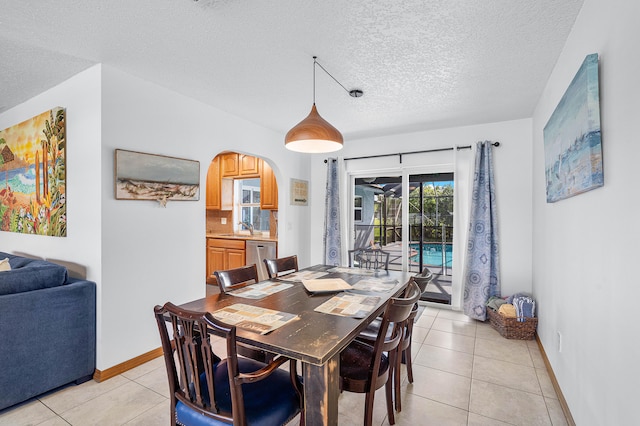 dining area with a textured ceiling, sink, and light tile patterned floors