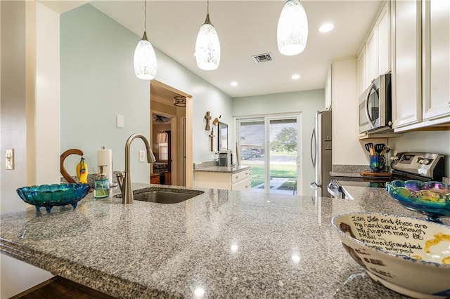 kitchen with sink, stainless steel appliances, decorative light fixtures, white cabinets, and light stone counters