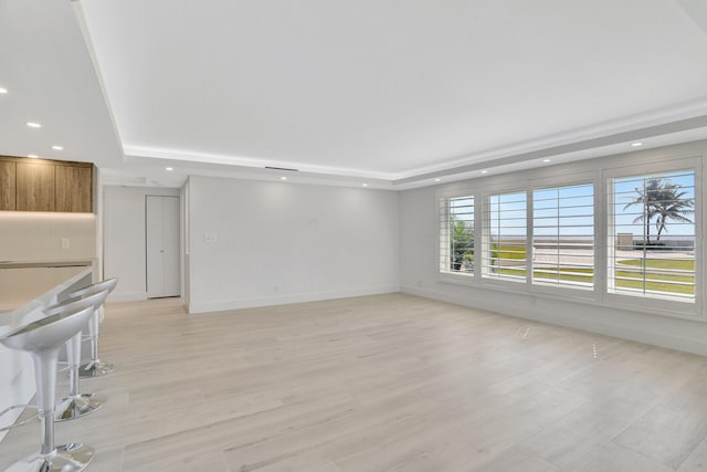 unfurnished living room featuring light hardwood / wood-style floors and a raised ceiling