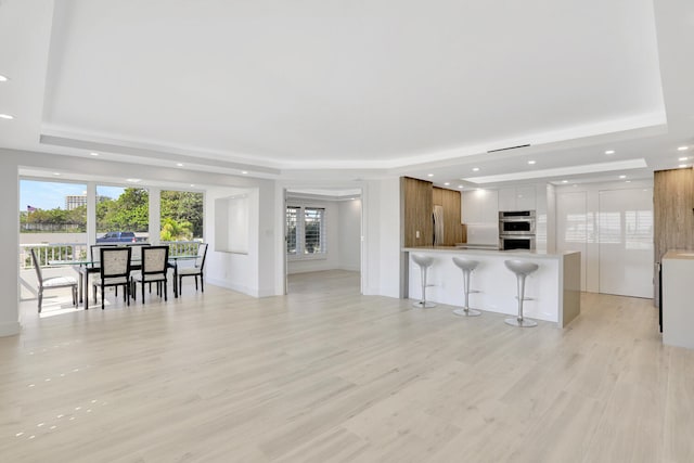 kitchen with a breakfast bar, white cabinets, kitchen peninsula, and a raised ceiling