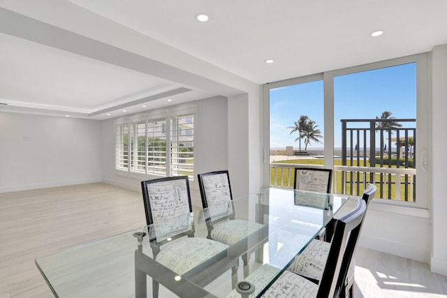 dining area with light hardwood / wood-style floors and a raised ceiling