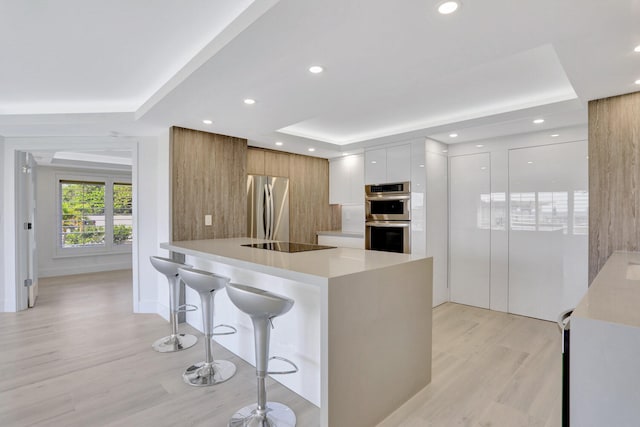 kitchen featuring light hardwood / wood-style floors, appliances with stainless steel finishes, a breakfast bar, and white cabinets