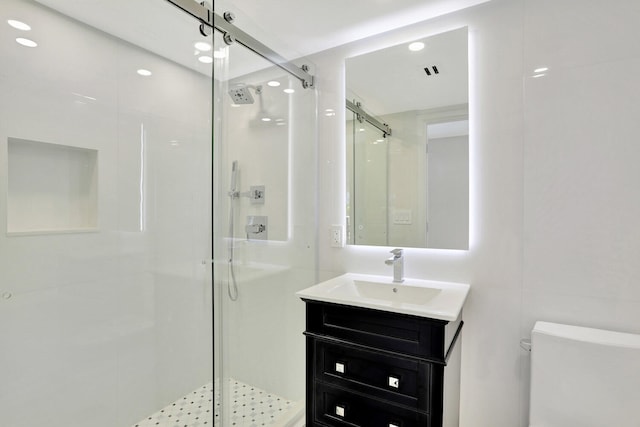 bathroom featuring vanity, a shower with shower door, and toilet