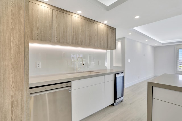 kitchen featuring dishwasher, sink, light wood-type flooring, beverage cooler, and white cabinets