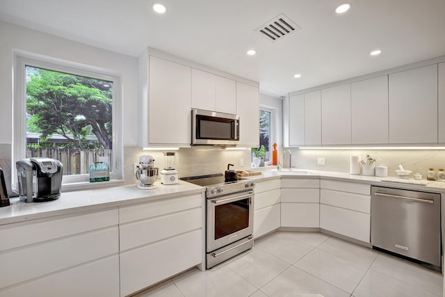 kitchen with sink, white cabinets, stainless steel appliances, and tasteful backsplash