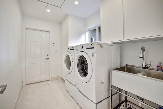 clothes washing area with sink, light tile patterned flooring, washer and dryer, and cabinets