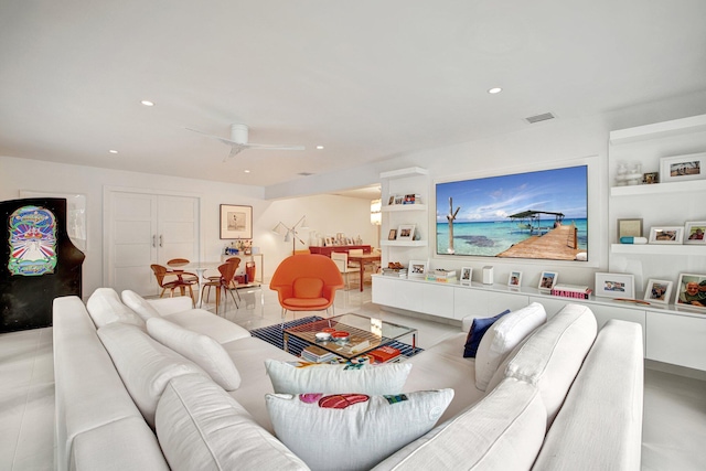 living room with ceiling fan and built in shelves