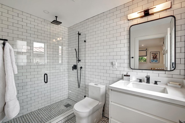 bathroom with toilet, walk in shower, vanity, and tile walls