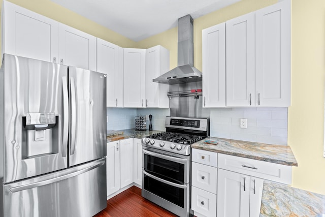 kitchen with white cabinetry, wall chimney range hood, light stone counters, and stainless steel appliances