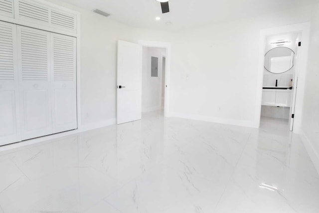 unfurnished bedroom featuring connected bathroom, ceiling fan, a closet, and electric panel