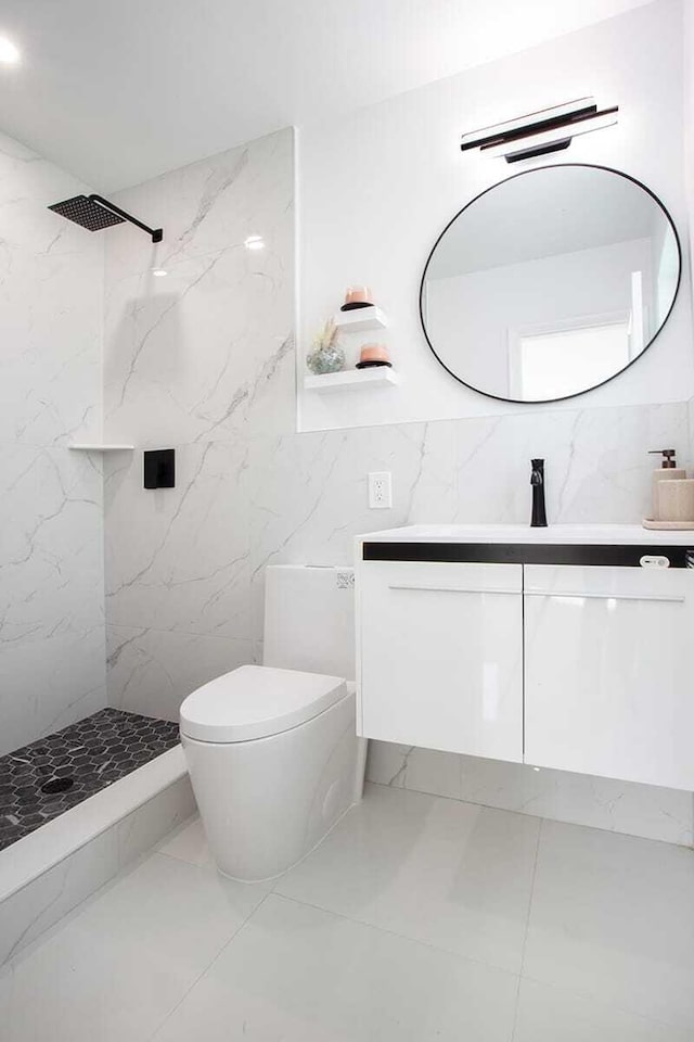 bathroom with toilet, vanity, a tile shower, and tile walls