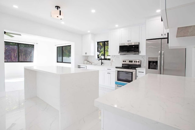 kitchen with white cabinets, light stone countertops, sink, pendant lighting, and stainless steel appliances