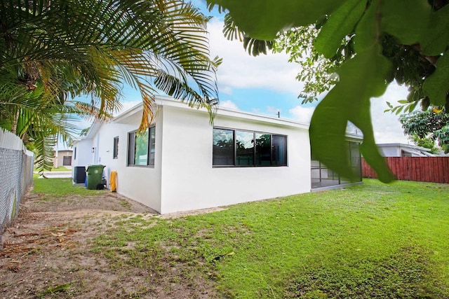 rear view of property with central air condition unit and a lawn