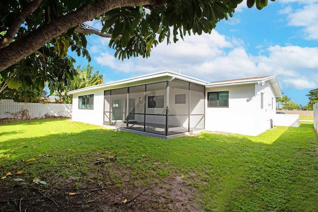 rear view of property featuring a sunroom and a lawn